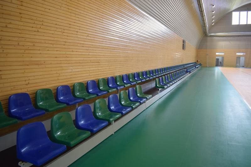 Tribuna se sedadly v moderní sportovní hale ve městě Bytča na Slovensku. Dřevěné obložení stěn a zelená sportovní podlaha v hale od společnosti HUPRO SYSTEMS SE.