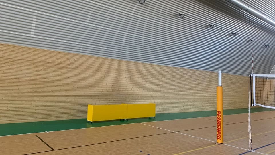 Interiér sportovní haly ve městě Bytča na Slovensku – dřevěné obložení stěn a volejbalové vybavení v moderní hale od HUPRO SYSTEMS SE.