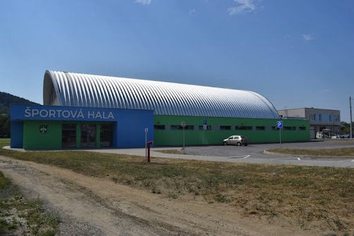 Moderní športová hala s obloukovou střechou ve slovenském městě Bytča. Budova s modro-zelenou fasádou slouží pro různé sportovní aktivity a byla realizována společností HUPRO SYSTEMS SE.