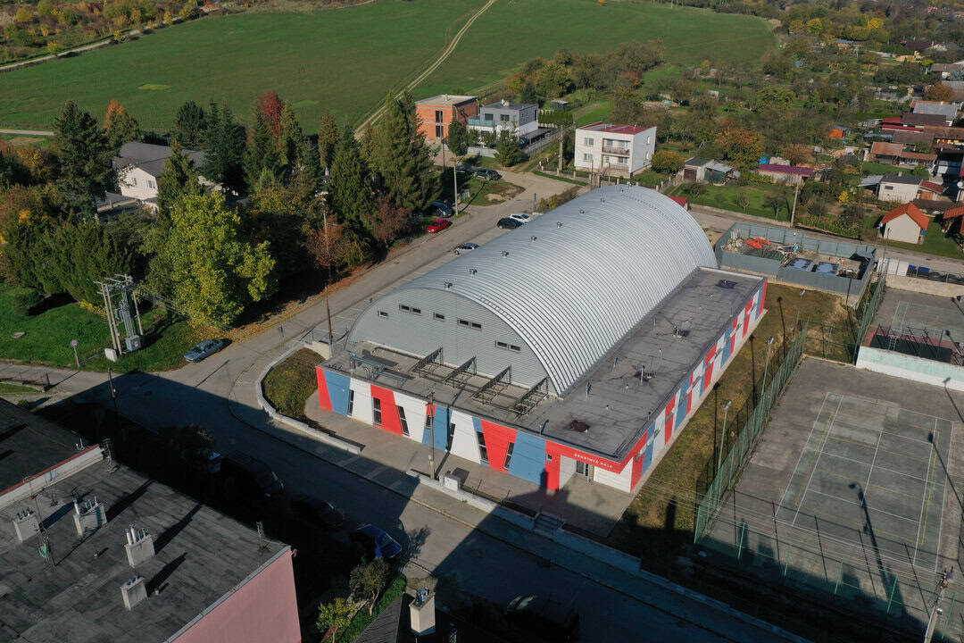 Boční letecký pohled na obloukovou montovanou ocelovou sportovní halu v Horní Srní postavenou systémem HUPRO SYSTEMS SE