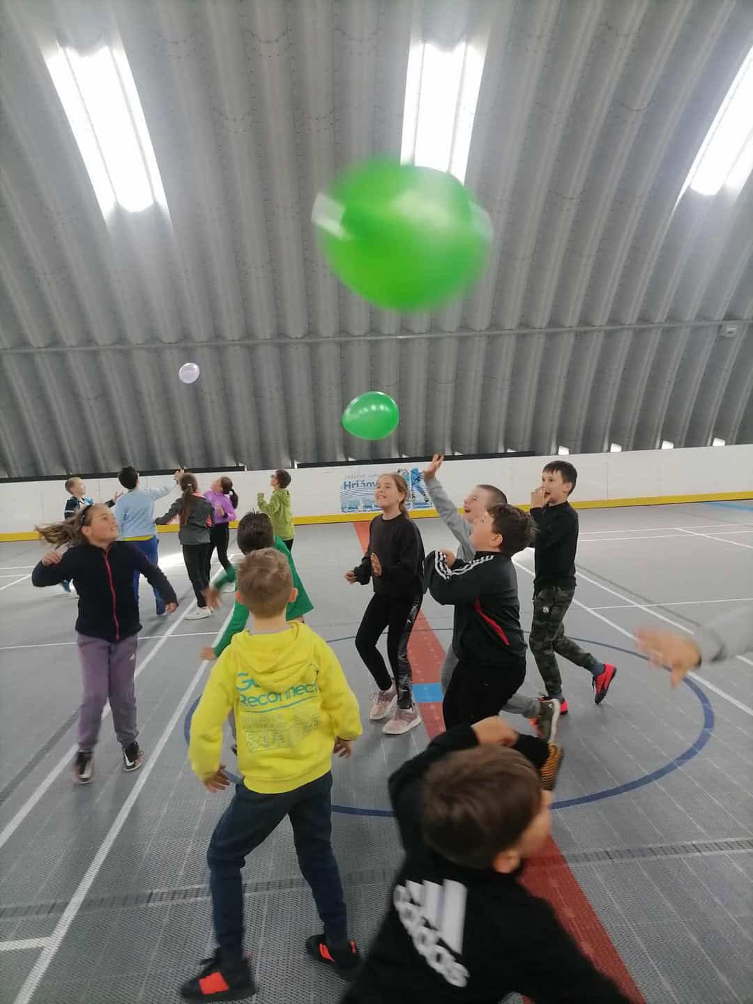 Děti při pohybových hrách v multifunkční montované hale v Hriňové s plastovým povrchem od společnosti HUPRO SYSTEMS SE, vhodné pro školní sportovní aktivity.