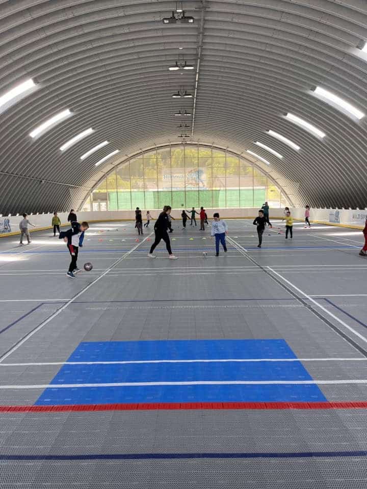 Děti hrají míčové hry v multifunkční montované hale v Hriňové od společnosti HUPRO SYSTEMS SE, s plastovým sportovním povrchem určeným pro různé sporty.