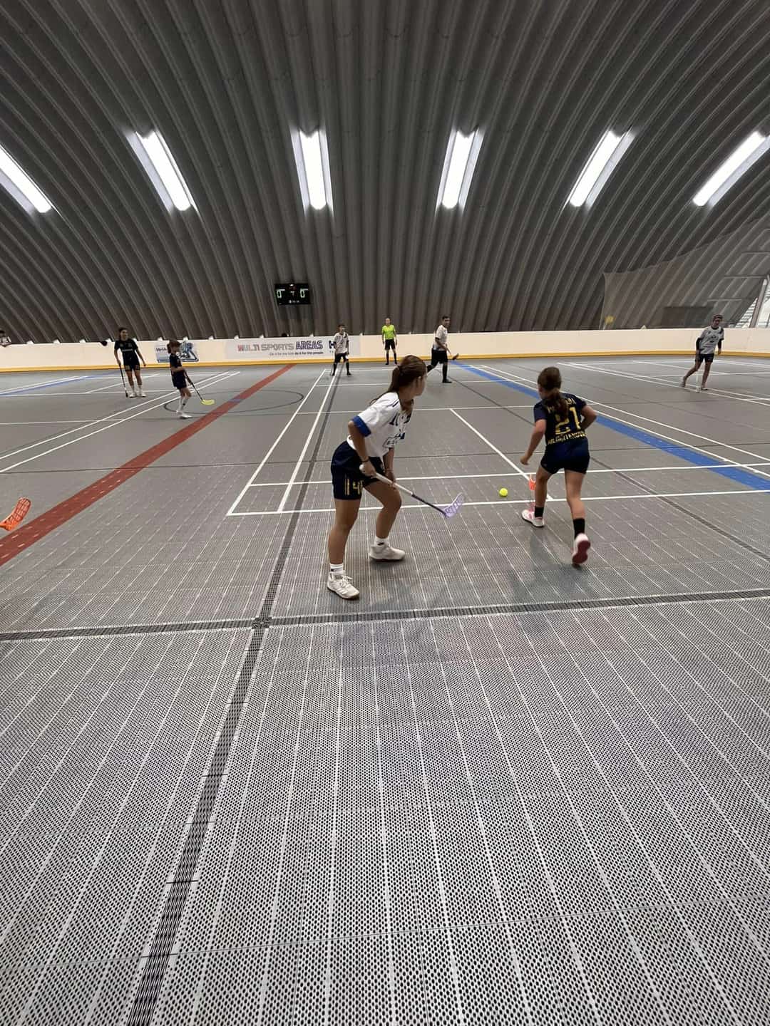 Dívky hrají florbal v moderní multifunkční hale v Hriňové s plastovým sportovním povrchem od společnosti HUPRO SYSTEMS SE, ideální pro tréninky i školní soutěže.