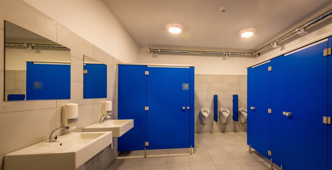 Moderní pánské toalety se zářivě modrými kabinkami v sportovní hale Kežmarok