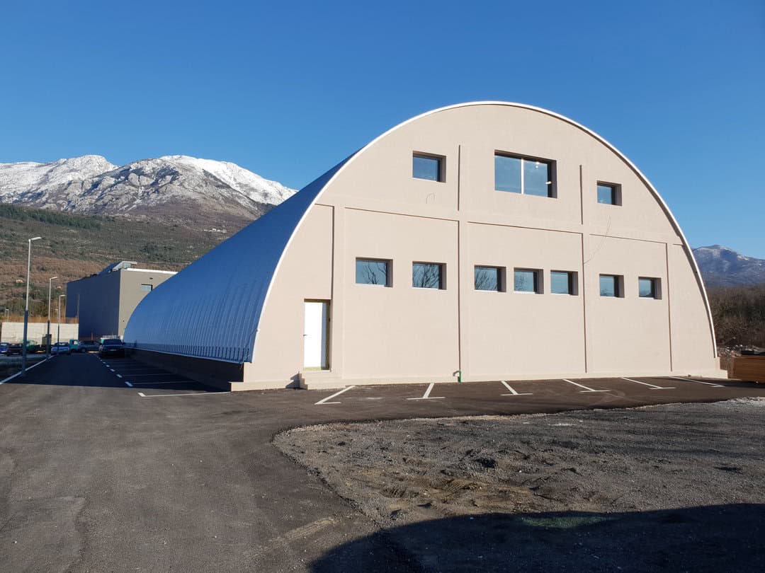 Montovaná ocelová sportovní hala Kotor – pohled na zadní část haly s horským pozadím, realizace HUPRO SYSTEMS SE.