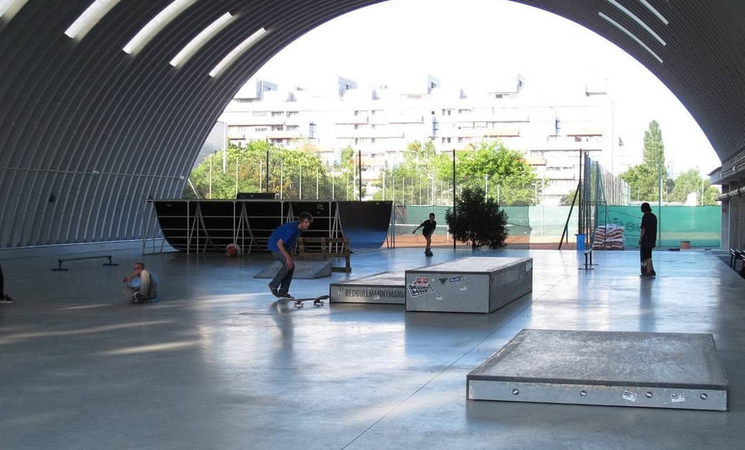 Interiér obloukové ocelové haly v Bratislavě Ružinově postavené systémem HUPRO SYSTEMS SE, využívané jako krytý skatepark s překážkami a rampami.