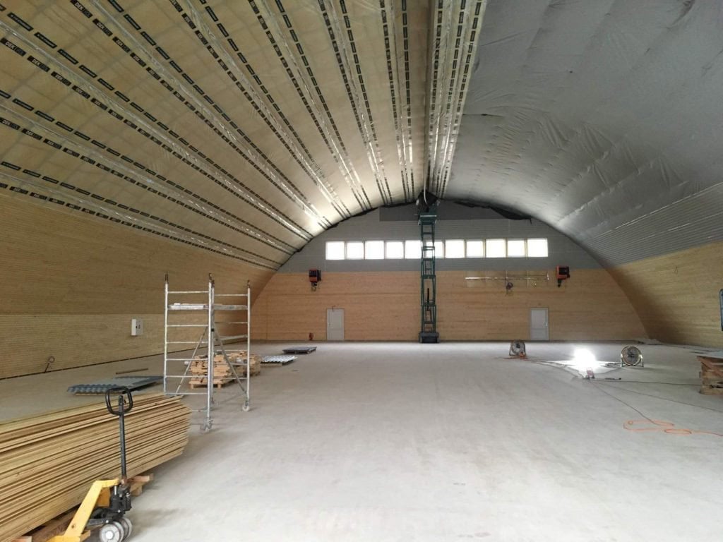 Interiér ocelové obloukové sportovní haly v Kynžvartu během dokončovacích prací, dřevěné obložení stěn, realizace HUPRO SYSTEMS SE.