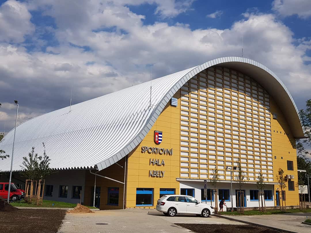 Oblouková montovaná ocelová multifunkční sportovní hala Praha Kbely s moderní architekturou a žluto-bílou fasádou.