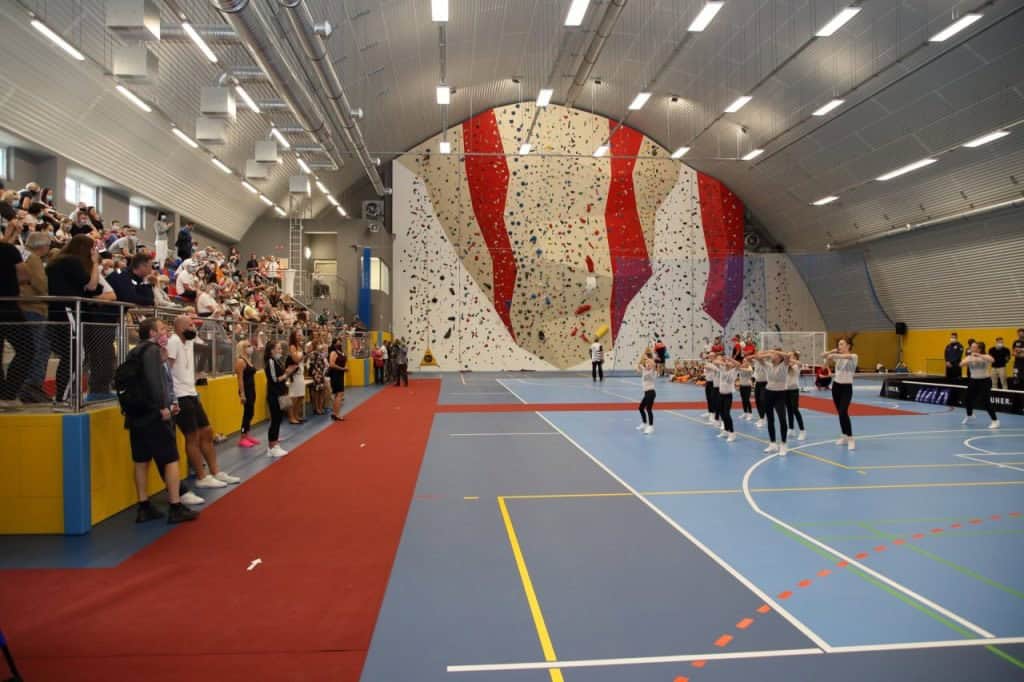 Multifunkční oblouková montovaná ocelová sportovní hala s tribunou, lezeckou stěnou a sportovní akcí, realizace HUPRO SYSTEMS SE.