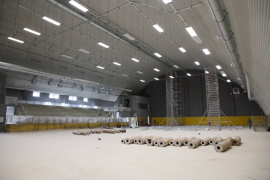 Interiér sportovní haly Praha Kbely během dokončovacích prací, montáž osvětlení a příprava podlahy, realizace HUPRO SYSTEMS SE