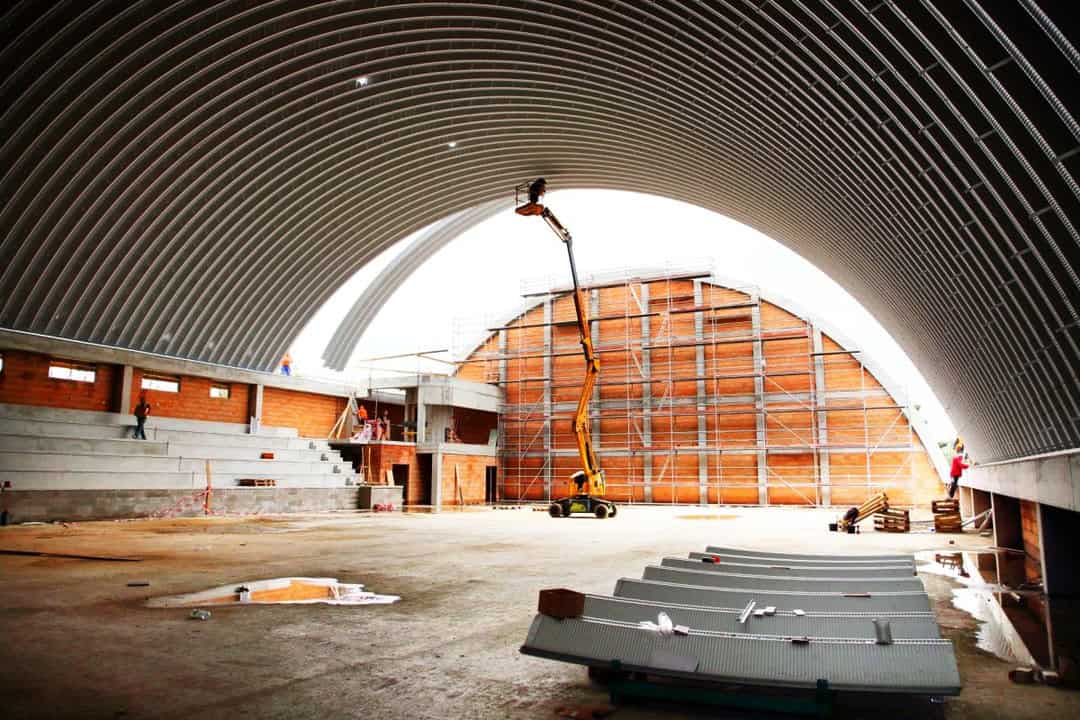 Interiér sportovní haly Praha Kbely během montáže obloukové střechy z ocelových panelů, pracovní plošina, realizace HUPRO SYSTEMS SE