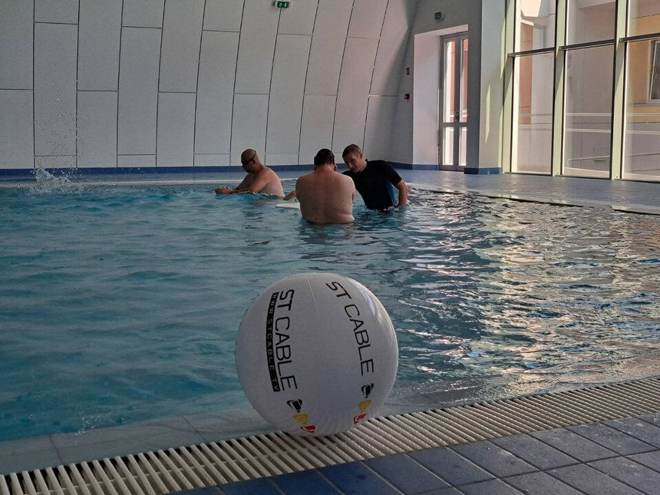 Montovaná ocelová oblouková plavecká hala Subotica – interiér menšího bazénu během cvičení ve vodě, realizace HUPRO SYSTEMS SE.