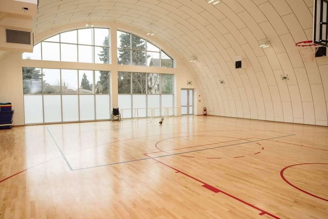 Montovaná ocelová sportovní hala Subotica – interiér tělocvičny s dřevěnou sportovní podlahou a proskleným čelním průčelím, realizace HUPRO SYSTEMS SE.