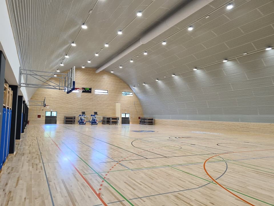 Víceúčelová montovaná ocelová sportovní hala Koprivnica, interiér s dřevěnou podlahou, basketbalovými koši a moderním LED osvětlením, projekt HUPRO SYSTEMS SE.