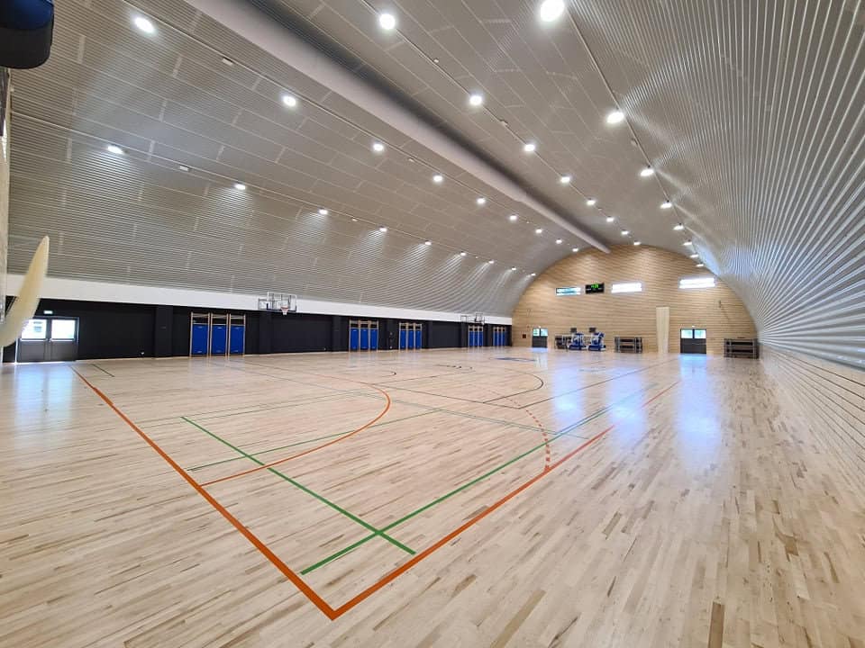Víceúčelová montovaná ocelová sportovní hala Koprivnica, interiér s dřevěnou podlahou a basketbalovým hřištěm, realizace HUPRO SYSTEMS SE.