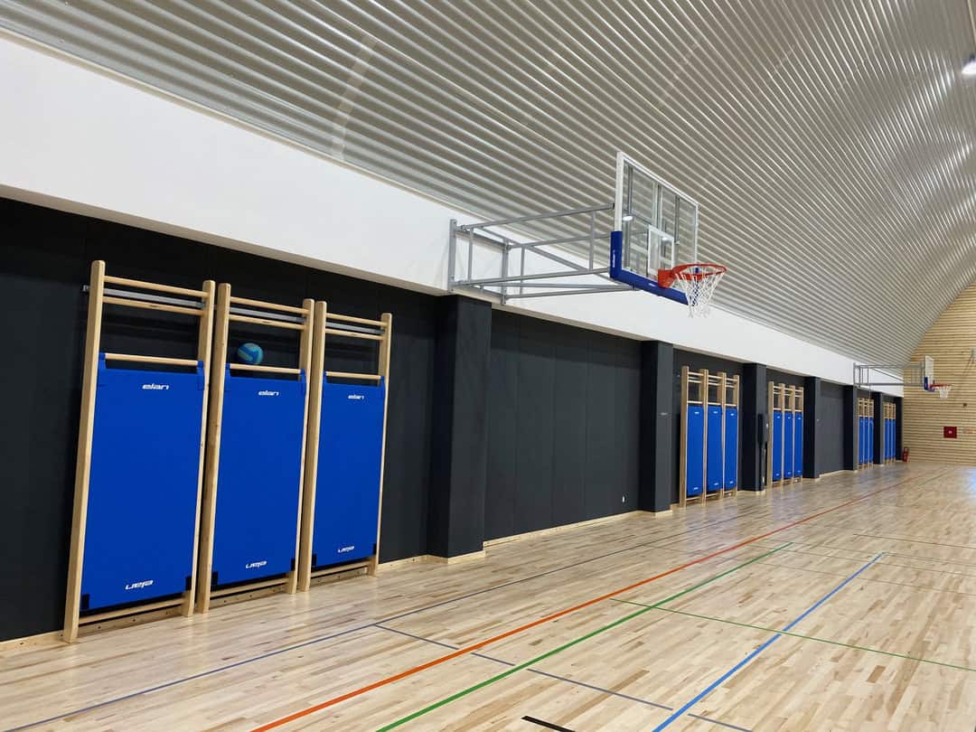Víceúčelová montovaná ocelová sportovní hala Koprivnica, interiér s basketbalovými koši, žebřinami a dřevěnou sportovní podlahou, projekt HUPRO SYSTEMS SE.