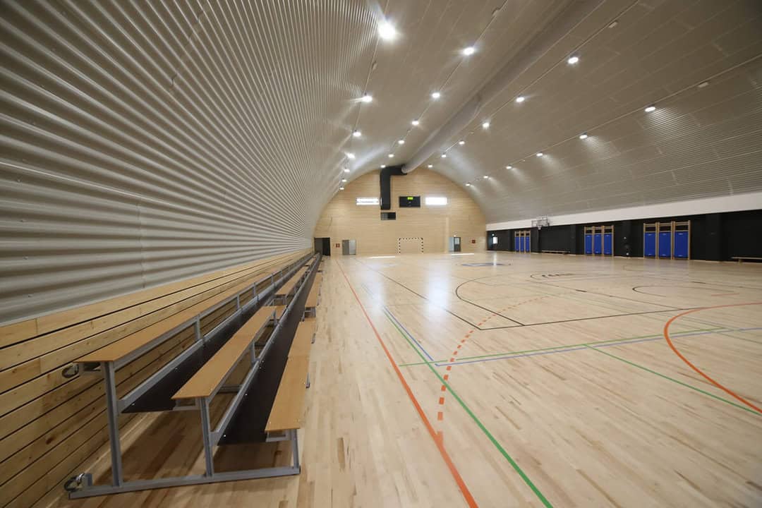 Víceúčelová montovaná ocelová sportovní hala Koprivnica, interiér s tribunami, basketbalovými koši a moderní dřevěnou podlahou, realizace HUPRO SYSTEMS SE.