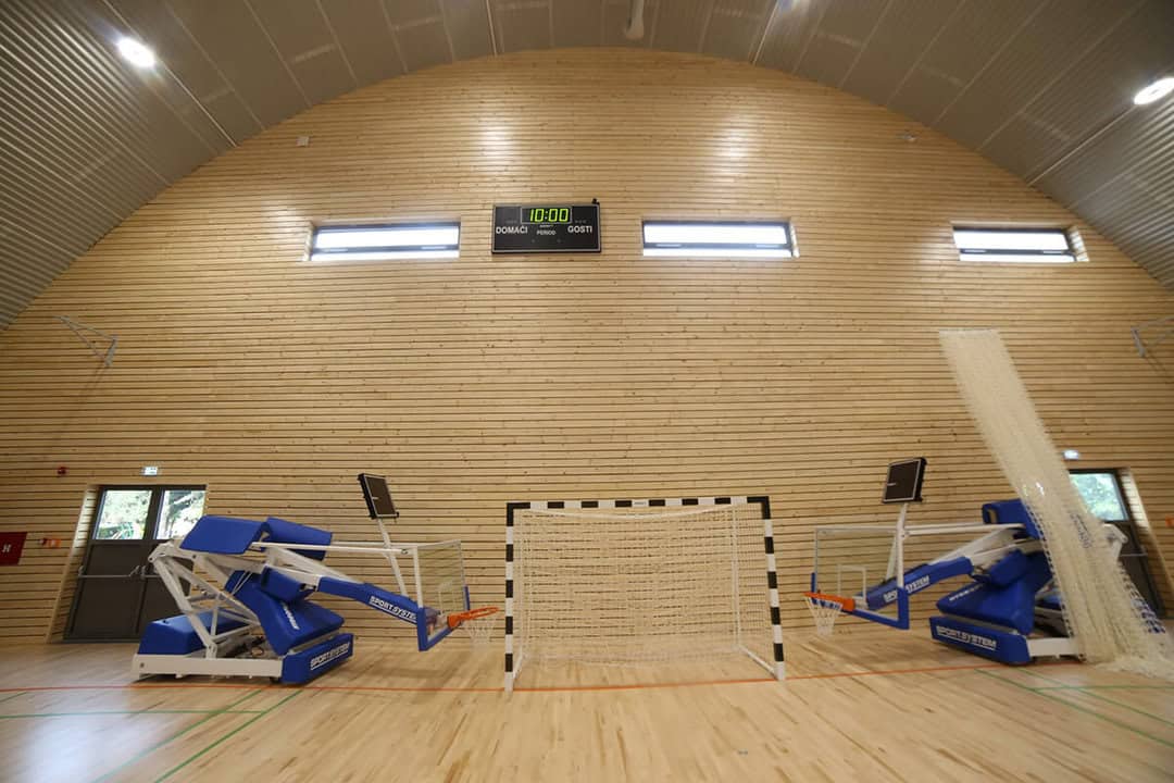 Oblouková sportovní hala Koprivnica, interiér s dřevěným obložením stěn, basketbalovými koši a brankou pro halové sporty, realizace HUPRO SYSTEMS SE.