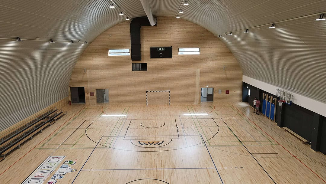 Víceúčelová montovaná ocelová sportovní hala Koprivnica, pohled shora na hrací plochu s basketbalovými a házenkářskými hřišti, dřevěná podlaha a tribuny, realizace HUPRO SYSTEMS SE.