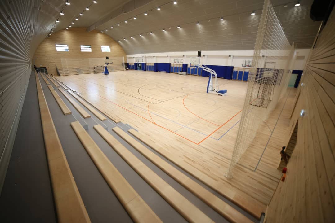 Víceúčelová montovaná ocelová sportovní hala Križevci s tribunami a basketbalovým hřištěm, moderní interiér s dřevěnou sportovní podlahou, realizace HUPRO SYSTEMS SE.