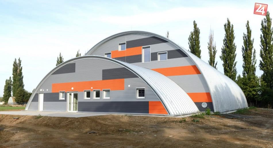 Sportovní hala Nitra Tulipanová – moderní oblouková stavba od HUPRO SYSTEMS SE s výraznou červeno-šedou fasádou a inovativním konstrukčním řešením.