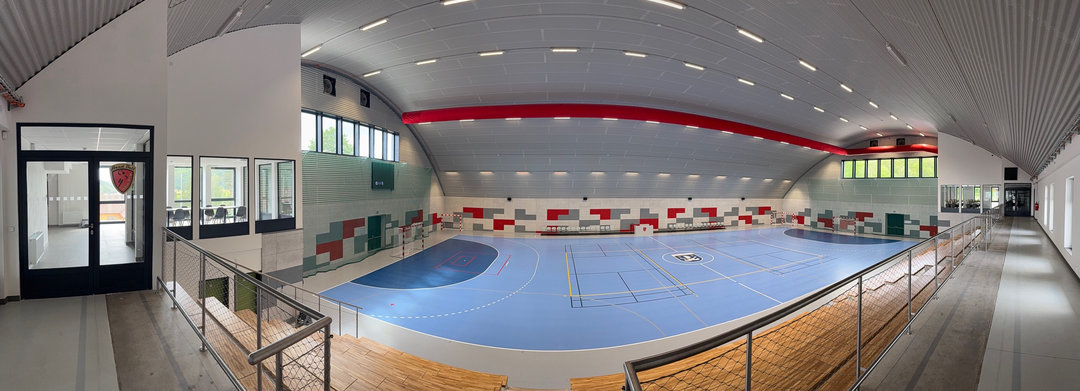 Panoramiczny widok z trybun na wnętrze hali sportowej Nové Bránice z niebieskim boiskiem wielofunkcyjnym. Realizacja firmy HUPRO SYSTEMS SE. Panoramiczny widok z trybun na wnętrze hali sportowej Nové Bránice z niebieskim boiskiem wielofunkcyjnym. Realizacja firmy HUPRO SYSTEMS SE.