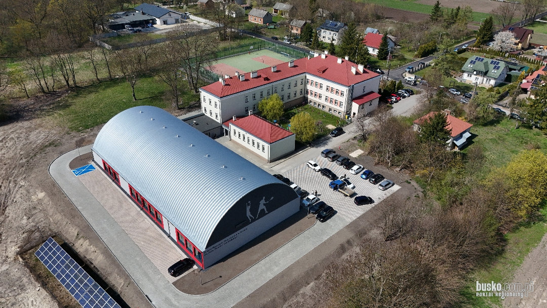 Widok z lotu ptaka na montowaną stalową łukową halę sportową Szaniec przy kompleksie szkolnym w Polsce. Realizacja firmy HUPRO SYSTEMS SE. Widok z lotu ptaka na montowaną stalową łukową halę sportową Szaniec przy kompleksie szkolnym w Polsce. Realizacja firmy HUPRO SYSTEMS SE.